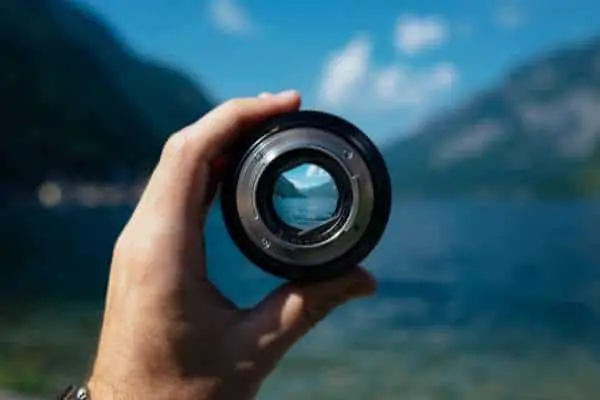 person holding a camera lens which is focusing a view