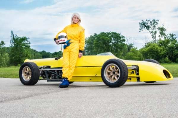 a female race car driver standing next to her race car