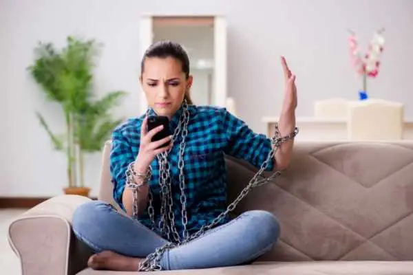 woman looking at her phone and being held in place with chains