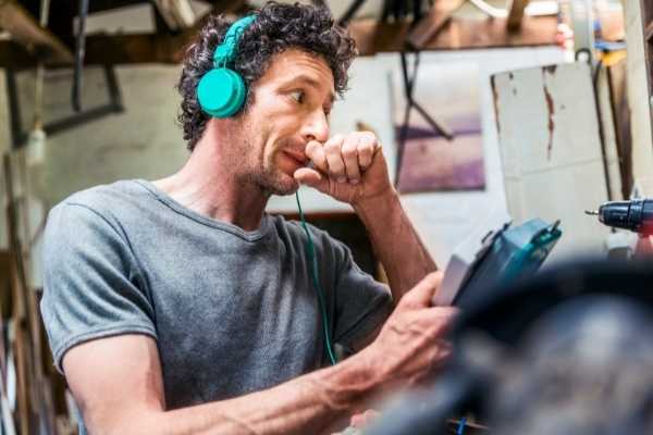 man wearing headphones and multitalking in messy environment