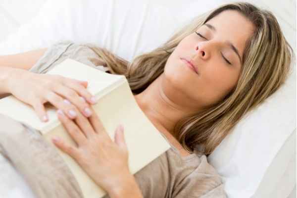 woman looking relaxed, lying down with a book on her chest