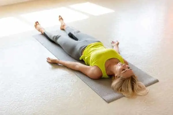 woman lying on a yoga mat doing yoga nidra