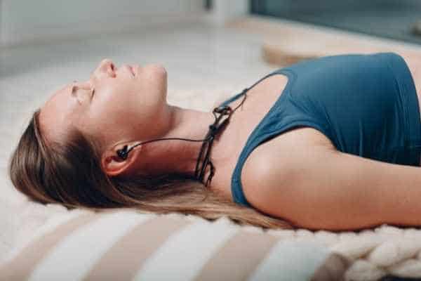 a relaxed woman lying down with earphone buds in her ears