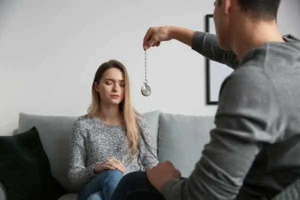 woman sitting in front of a hypnotist holding a pocket watch