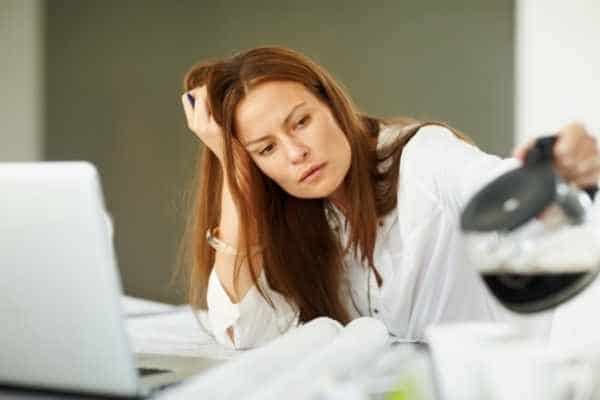 tired woman looking at a cup of coffee being poured