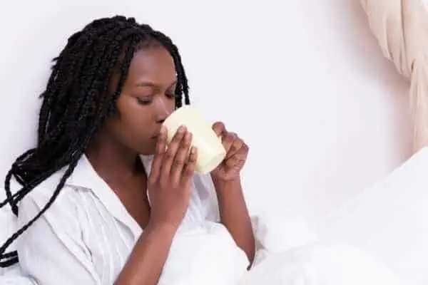 woman in bed drinking a cup of coffee