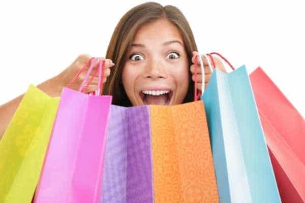 a woman smiling and holding multiple shopping bags