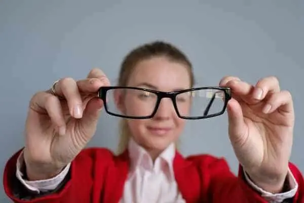woman holding eye glasses in front of her face