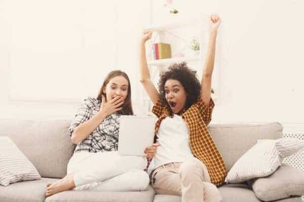 two friends very excited by what they are watching on an iPad