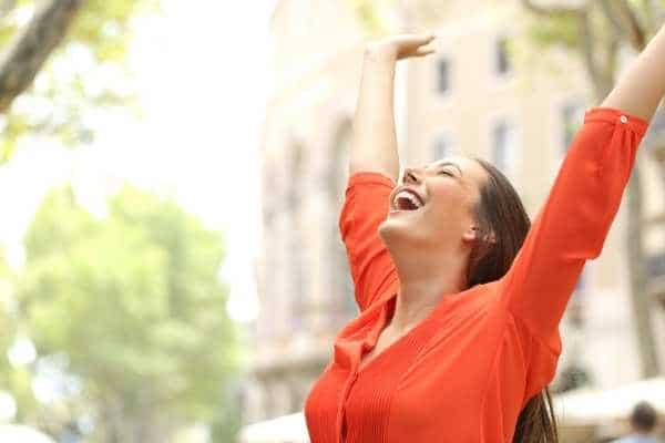 a woman outside in the sun looking happy and excited