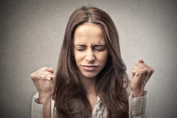 a woman with closed eyes clenching her fists