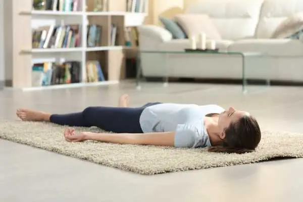 woman lying down on a carpet and meditating