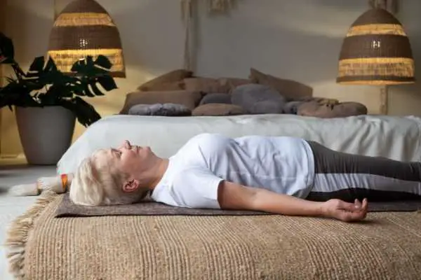 older woman lying on a yoga mat meditating