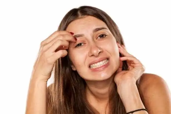 woman picking the skin on her face