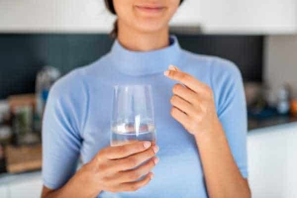 woman taking a sleep cocktail capsule