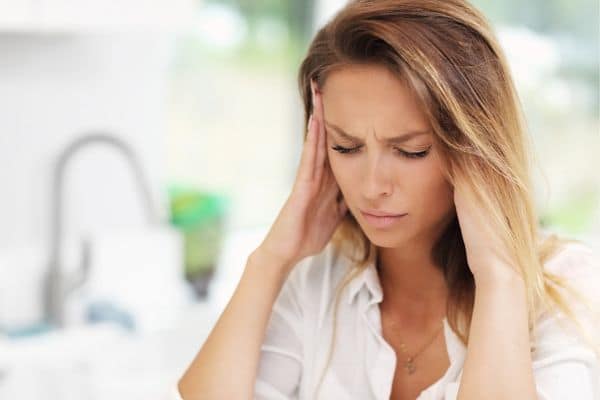 woman with headache pressing hands to temples