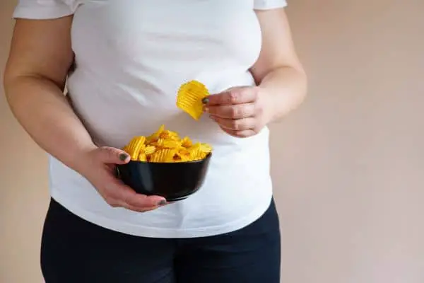 overweight woman eating a bowl of chips