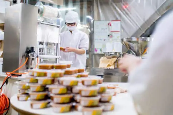 Workers at a plant with processed food in small plastic cups