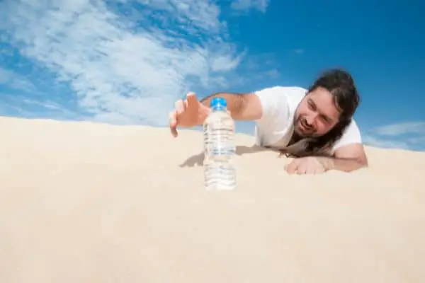 thirsty man in a desert reaching for a water bottle